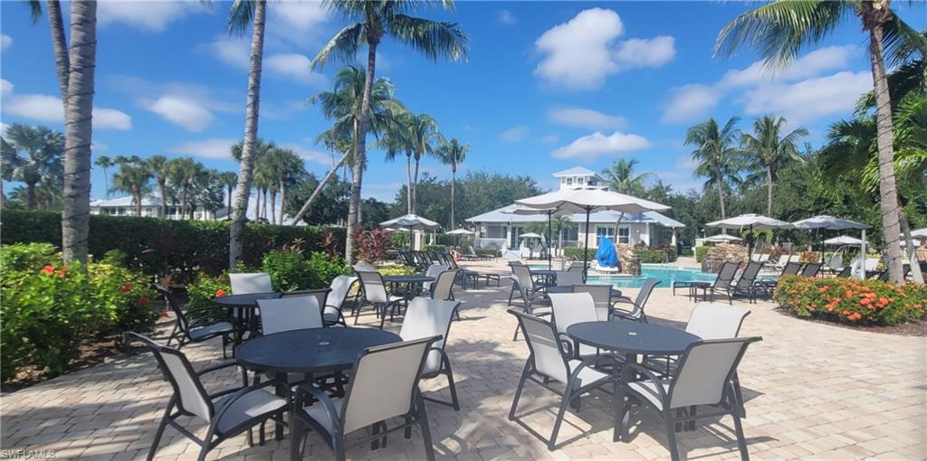7920 Mahogany Run Lane, Unit 1015 Naples, FL 34113 - Photo 10 of 41 a view of a patio with table and chairs potted plants and palm trees