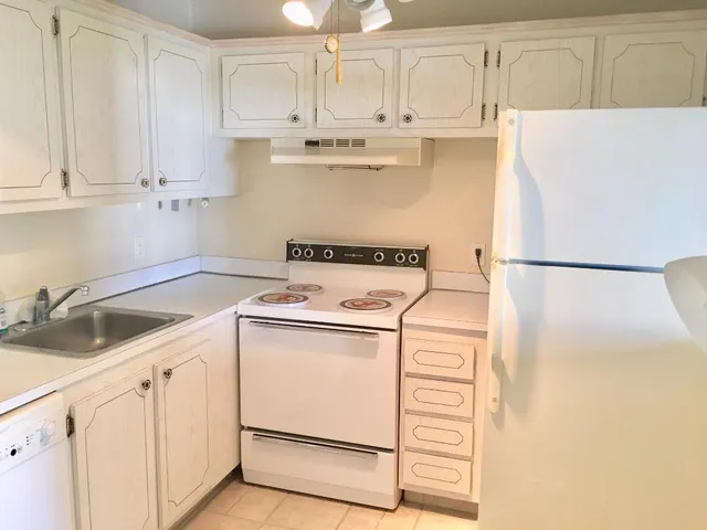a kitchen with stainless steel appliances white cabinets and white refrigerator