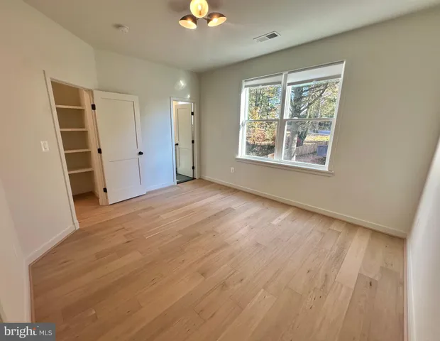 a view of an empty room with a window and wooden floor