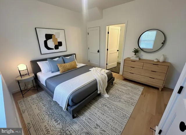 a bedroom with a bed large mirror and lamp on desk