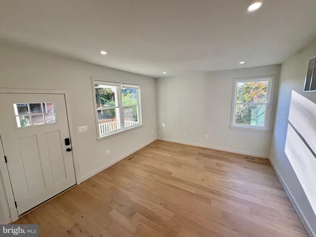 a view of an empty room with a window and wooden floor