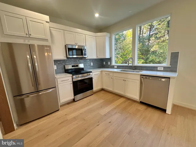 a kitchen with stainless steel appliances granite countertop a refrigerator a stove a sink and a microwave