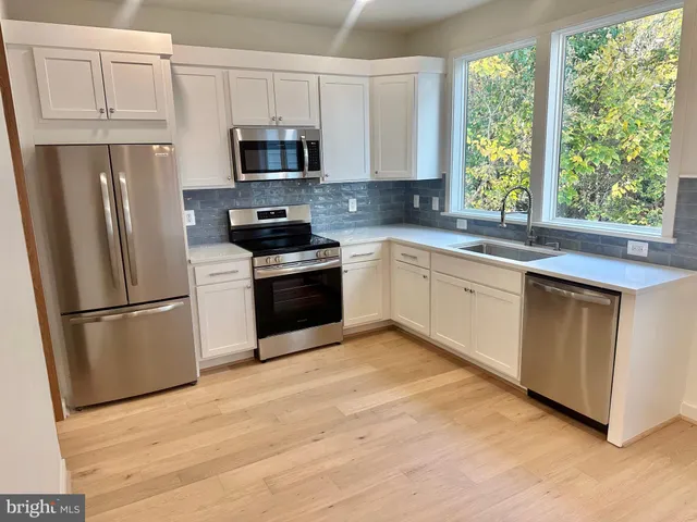a kitchen with white cabinets stainless steel appliances and window