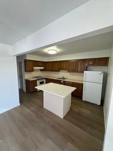 a kitchen with a sink a stove top oven a chimney and a hard wood floor