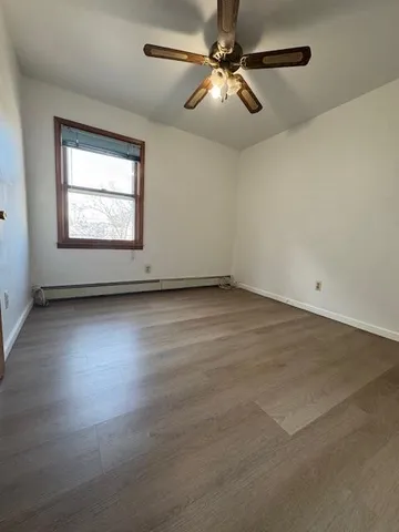 an empty room with wooden floor chandelier fan and windows