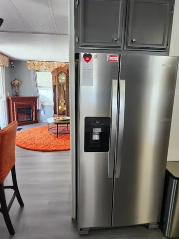 a utility room with stainless steel appliances wooden cabinet and a refrigerator