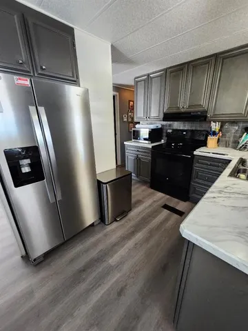 a kitchen with granite countertop wooden cabinets a refrigerator and a stove