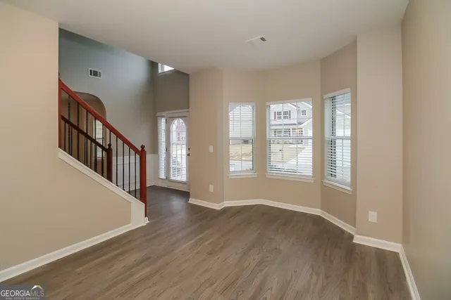 a view of an empty room with wooden floor and a window