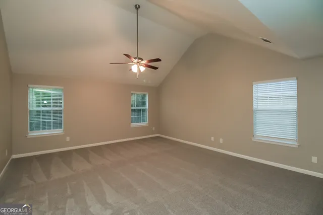 an empty room with windows and fan