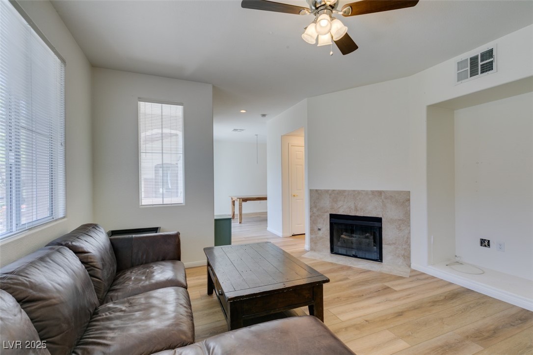 10220 Delray Beach Avenue, Unit 103 Las Vegas, NV 89129 - Photo 12 of 42 Living area with light wood-style flooring, visible vents, baseboards, a tiled fireplace, and a ceiling fan