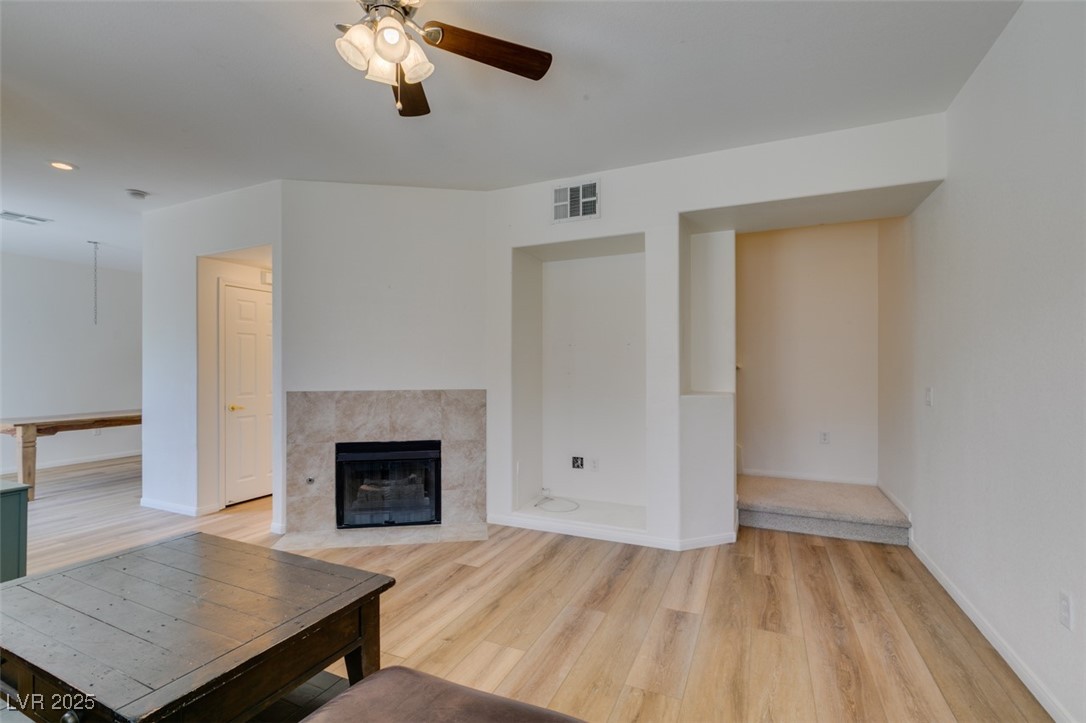 10220 Delray Beach Avenue, Unit 103 Las Vegas, NV 89129 - Photo 13 of 42 Living area featuring a tile fireplace, a ceiling fan, baseboards, visible vents, and light wood-style floors