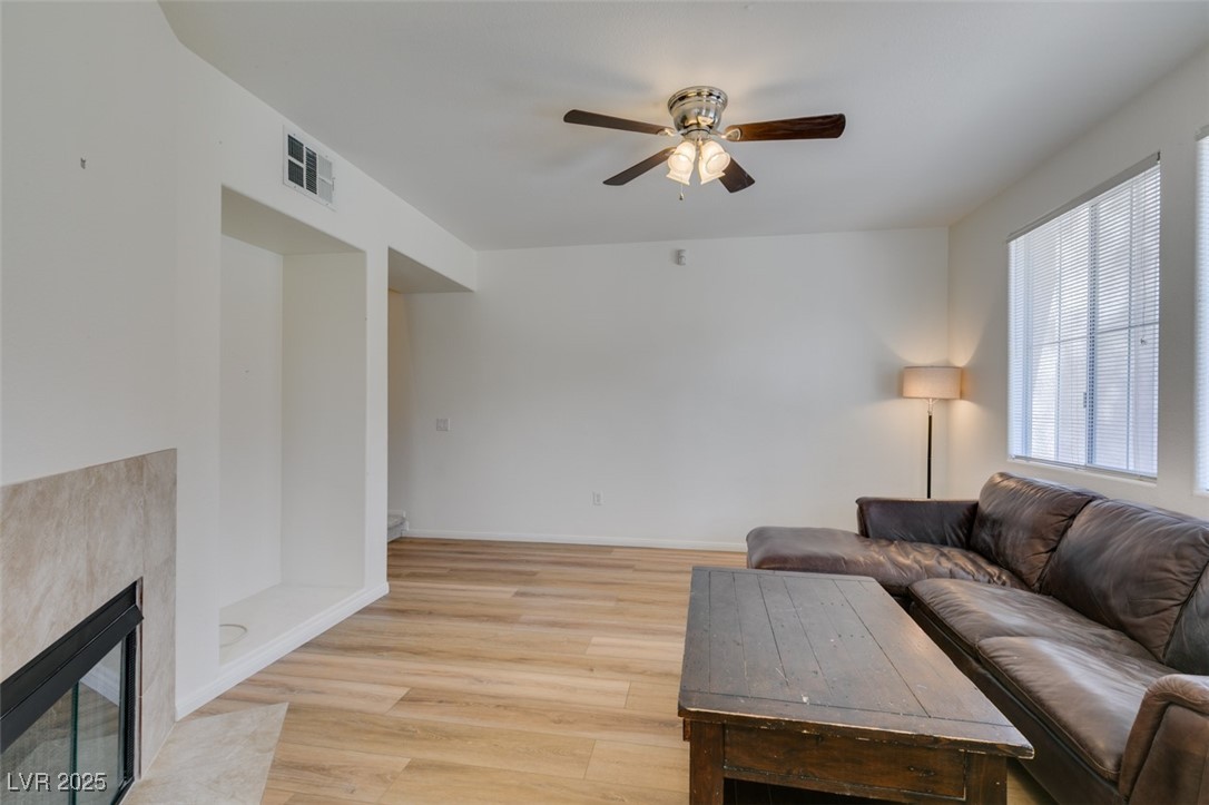 10220 Delray Beach Avenue, Unit 103 Las Vegas, NV 89129 - Photo 5 of 42 Living area with light wood-style flooring, visible vents, baseboards, a fireplace, and a ceiling fan