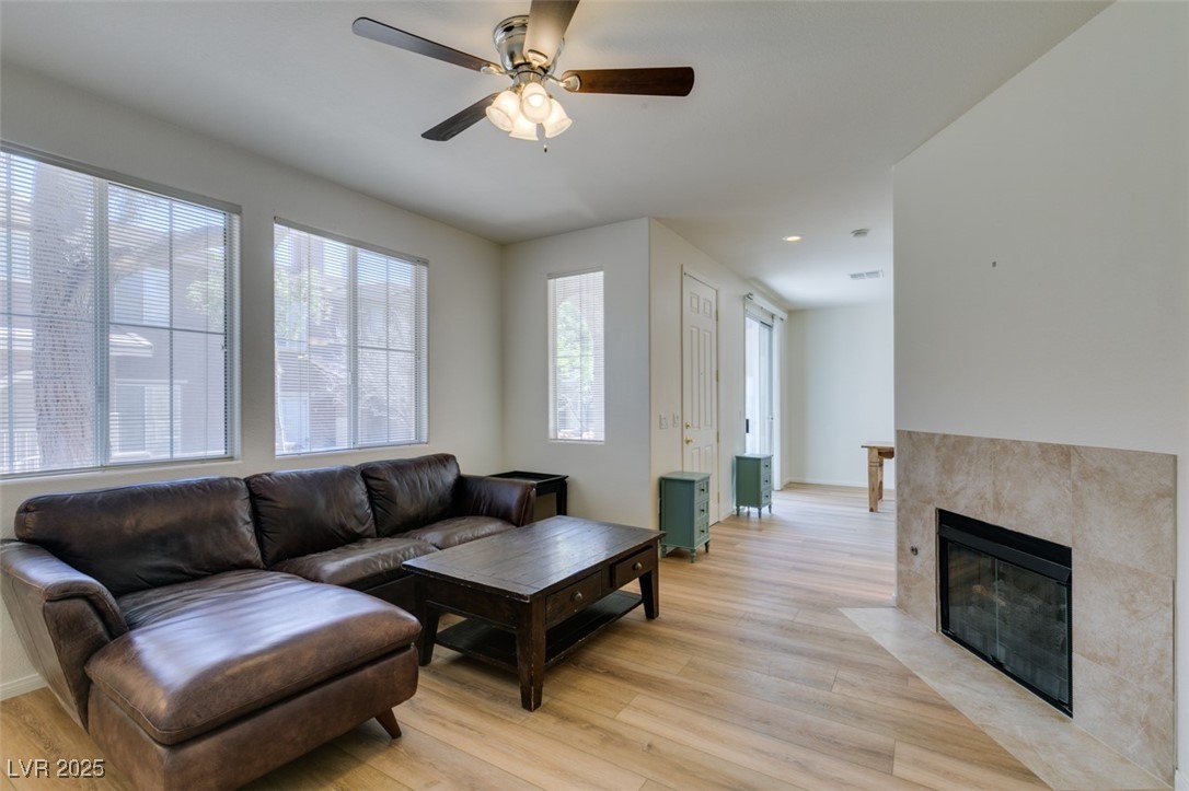 10220 Delray Beach Avenue, Unit 103 Las Vegas, NV 89129 - Photo 10 of 42 Living area featuring baseboards, light wood-style flooring, a tile fireplace, and a ceiling fan