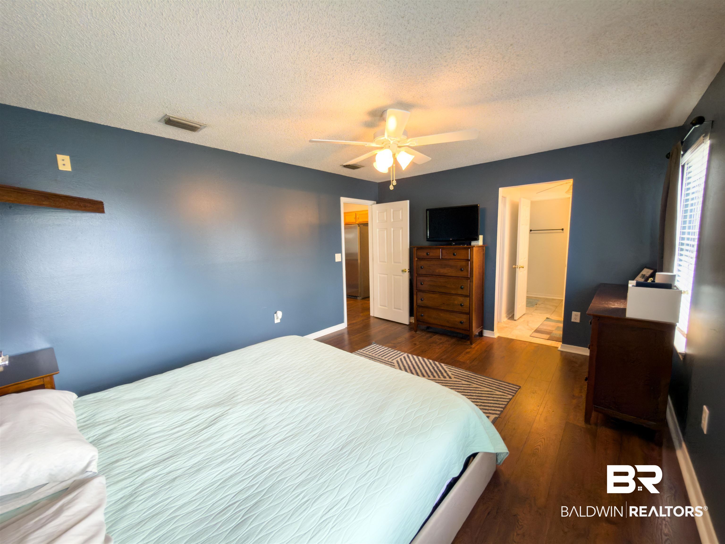 129 Pennbrooke Loop Foley, AL 36535 - Photo 26 of 44 Bedroom with dark wood-style flooring, a ceiling fan, a textured ceiling, and ensuite bath
