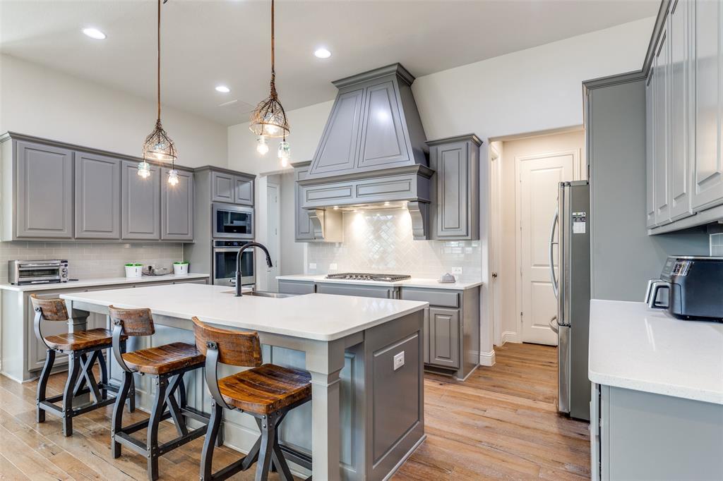 15193 Basket Oak Road Frisco, TX 75035 - Photo 11 of 40 a open kitchen with stainless steel appliances granite countertop a stove top oven a refrigerator a sink and chairs