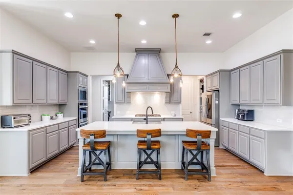 a kitchen with stainless steel appliances kitchen island granite countertop a sink cabinets and wooden floor