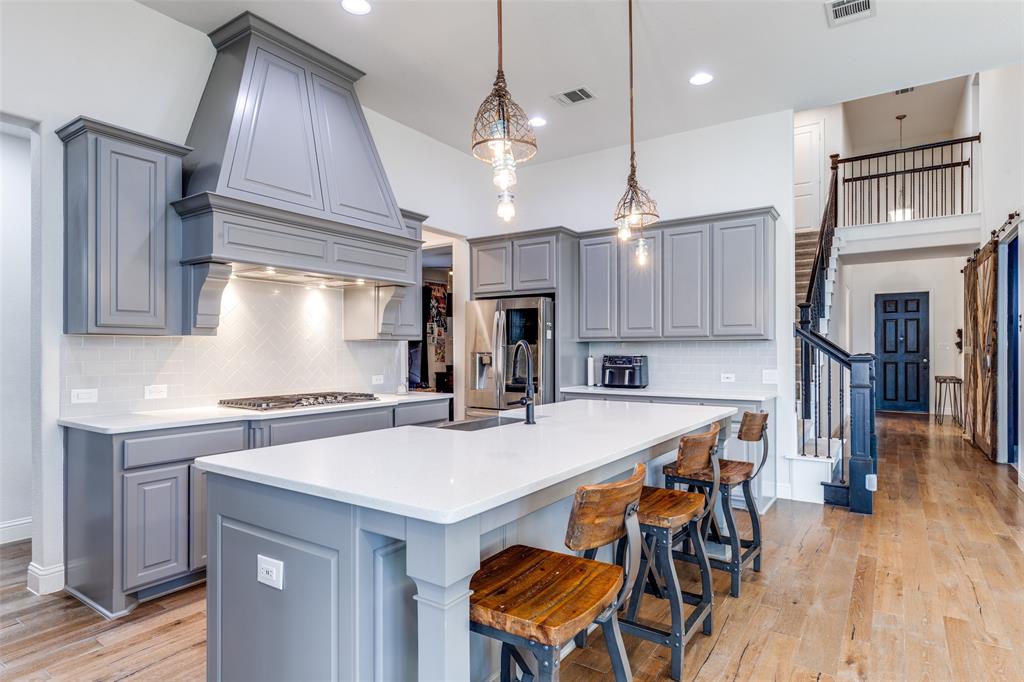 15193 Basket Oak Road Frisco, TX 75035 - Photo 13 of 40 a kitchen with stainless steel appliances granite countertop a kitchen island a stove a table and chairs in it