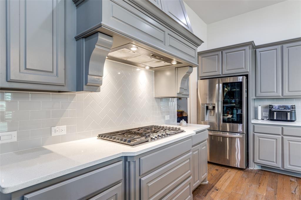 15193 Basket Oak Road Frisco, TX 75035 - Photo 14 of 40 a kitchen with a stove and white cabinets