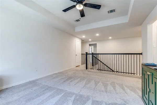 en empty room with stairs and a ceiling fan