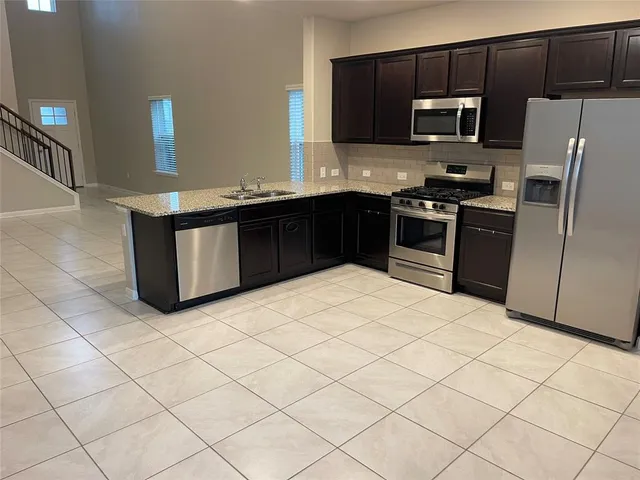 a kitchen with stainless steel appliances granite countertop a refrigerator and a stove top oven