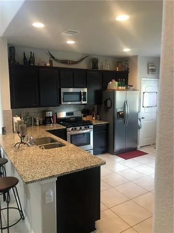 a kitchen with kitchen island granite countertop a sink counter top space appliances and cabinets