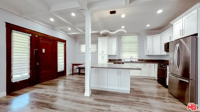 a kitchen with stainless steel appliances granite countertop a refrigerator a sink dishwasher a stove and white cabinets with wooden floor