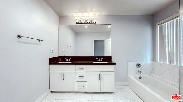 a bathroom with a sink a large mirror and a bathtub