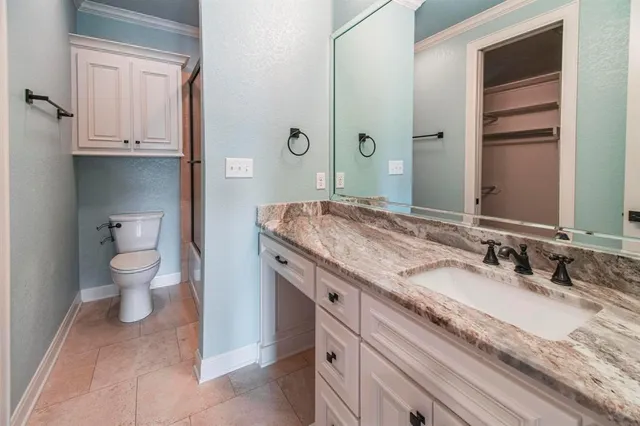 a bathroom with a granite countertop sink a toilet and a mirror