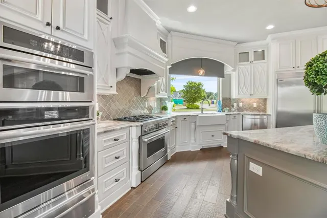 a kitchen with granite countertop white cabinets and white stainless steel appliances