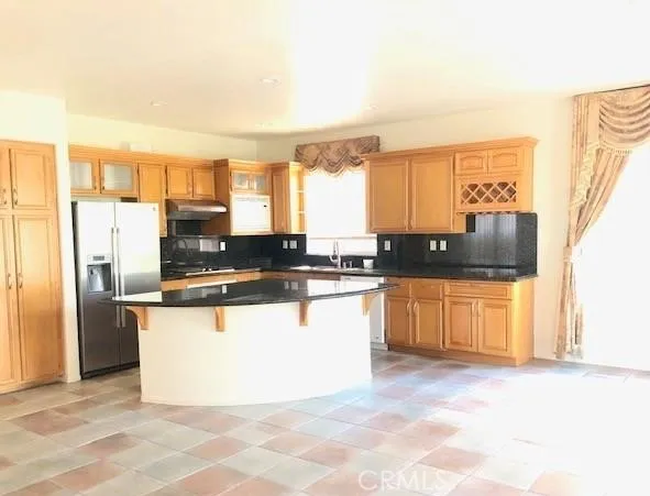 a large kitchen with a refrigerator a stove a sink a microwave and cabinets