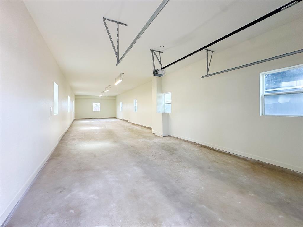 153 Cabrera Street Oak Point, TX 75068 - Photo 14 of 22 Spacious garage featuring a concrete floor, multiple windows, overhead fluorescent lighting, a garage door opener, and painted walls