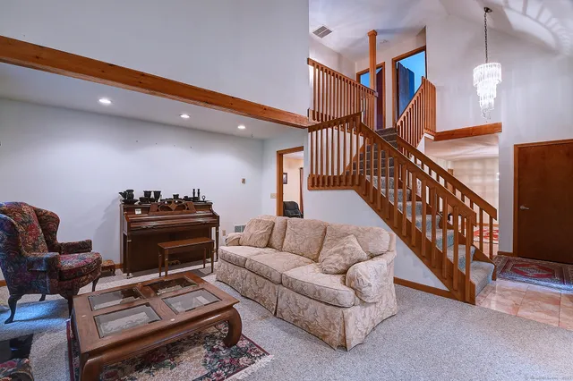a living room with furniture a piano and a bookshelf
