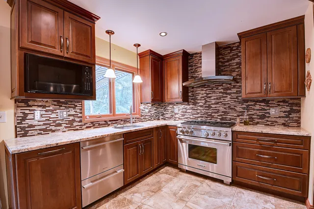 a kitchen with stainless steel appliances granite countertop a stove microwave and cabinets