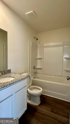 a bathroom with a granite countertop toilet a sink and a mirror