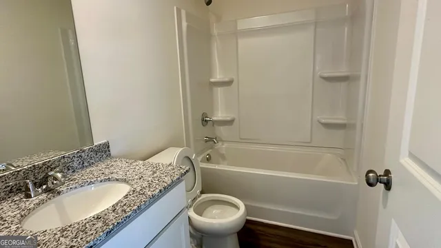 a bathroom with a granite countertop toilet a sink and a bathtub
