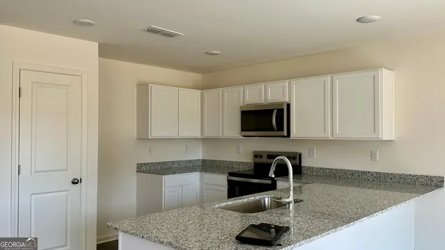 a kitchen with granite countertop a sink a stove and a microwave