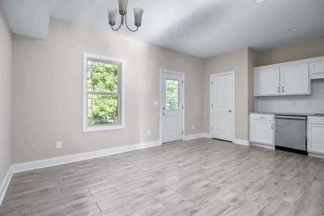 an empty room with wooden floor cabinet and windows