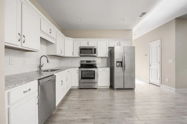a kitchen with stainless steel appliances granite countertop a refrigerator and a stove top oven