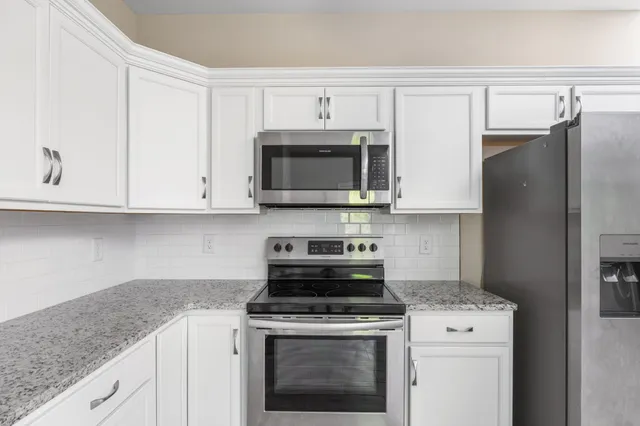 a kitchen with granite countertop white cabinets and stainless steel appliances
