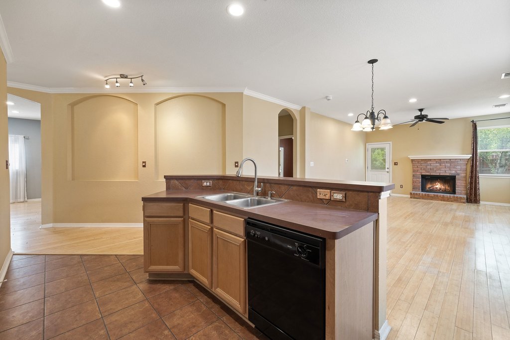 347 Spring Drive Kyle, TX 78640 - Photo 11 of 40 An inviting open-concept layout connects the kitchen, dining area, and living space, anchored by a brick fireplace.