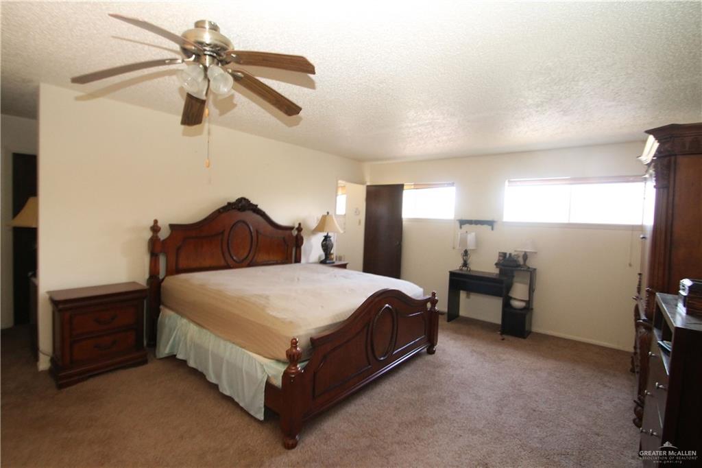 110 Avenida Morelos Rancho Viejo, TX 78575 - Photo 14 of 19 a spacious bedroom with a bed and a chandelier