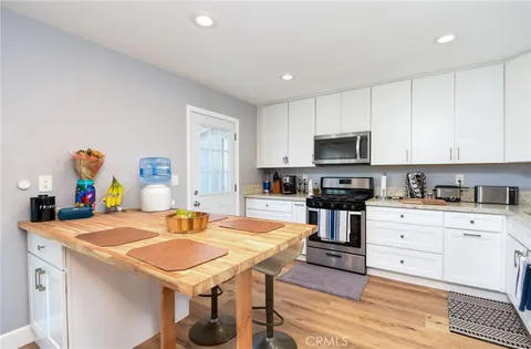 a kitchen with stainless steel appliances a refrigerator a stove a sink cabinets and a dining table