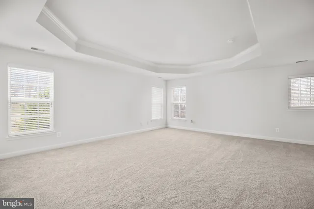 an empty room with wooden floor ceiling fan and windows