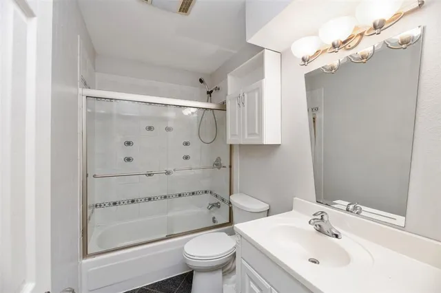 a bathroom with a bathtub shower sink vanity and toilet