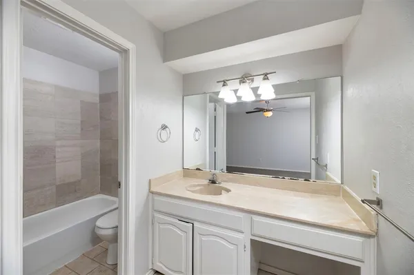 a bathroom with a granite countertop sink a toilet and shower