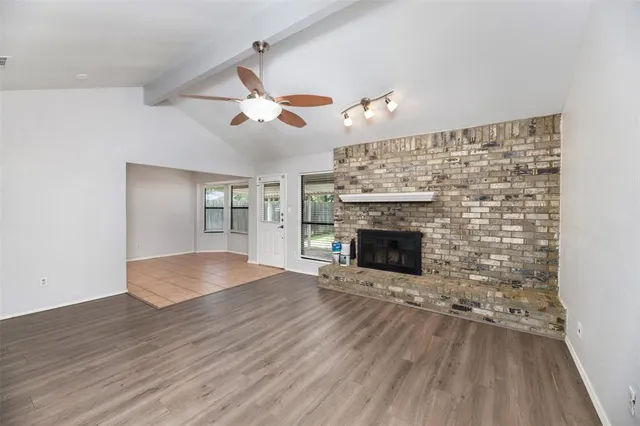 a view of an empty room with wooden floor fireplace and a window