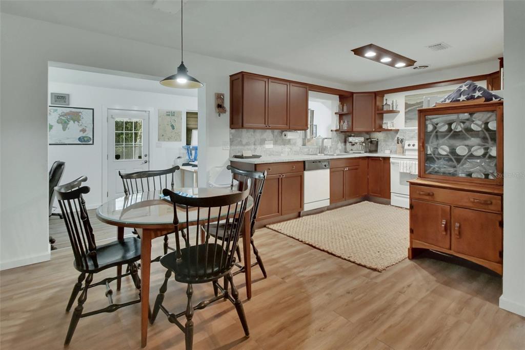 22040 Blue Creek Lodge Road Astor, FL 32102 - Photo 11 of 42 a kitchen with stainless steel appliances granite countertop a stove top oven a sink a dining table and chairs with wooden floor