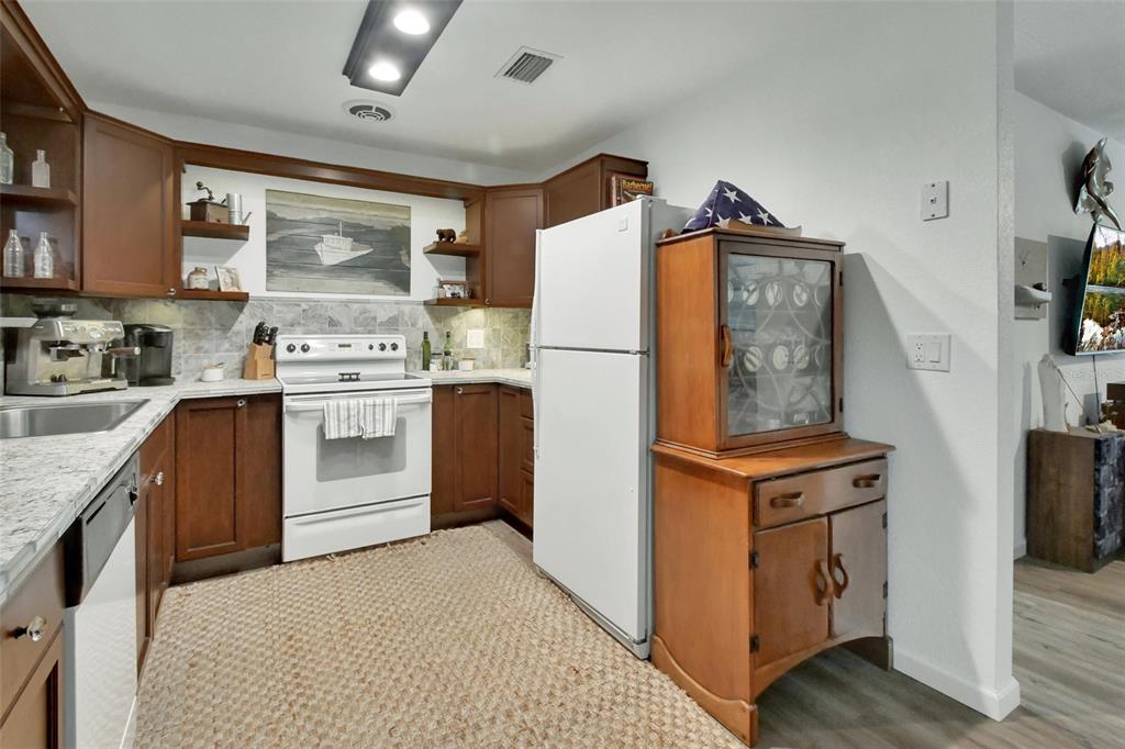 22040 Blue Creek Lodge Road Astor, FL 32102 - Photo 14 of 42 a kitchen with stainless steel appliances granite countertop a refrigerator a stove a sink dishwasher and wooden cabinets with wooden floor