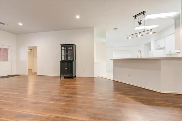 a view of an empty room with wooden floor and windows