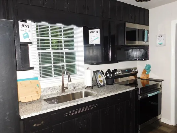 a kitchen with granite countertop a sink and a refrigerator